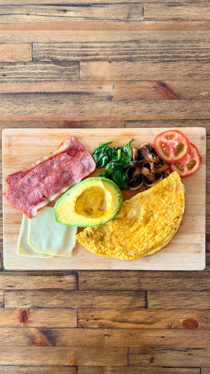 Delicious breakfast platter with omelette, avocado, and fresh salad ingredients.