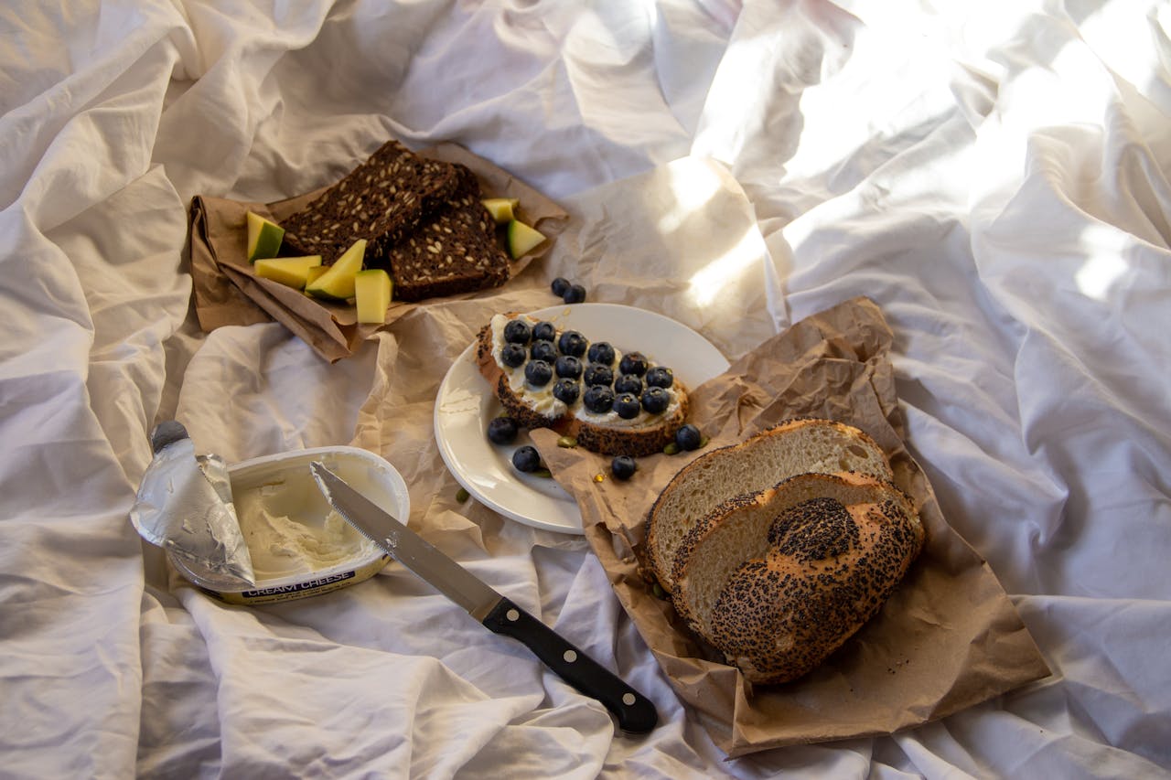 Delicious breakfast in bed featuring blueberries, cream cheese, and fresh bread slices.