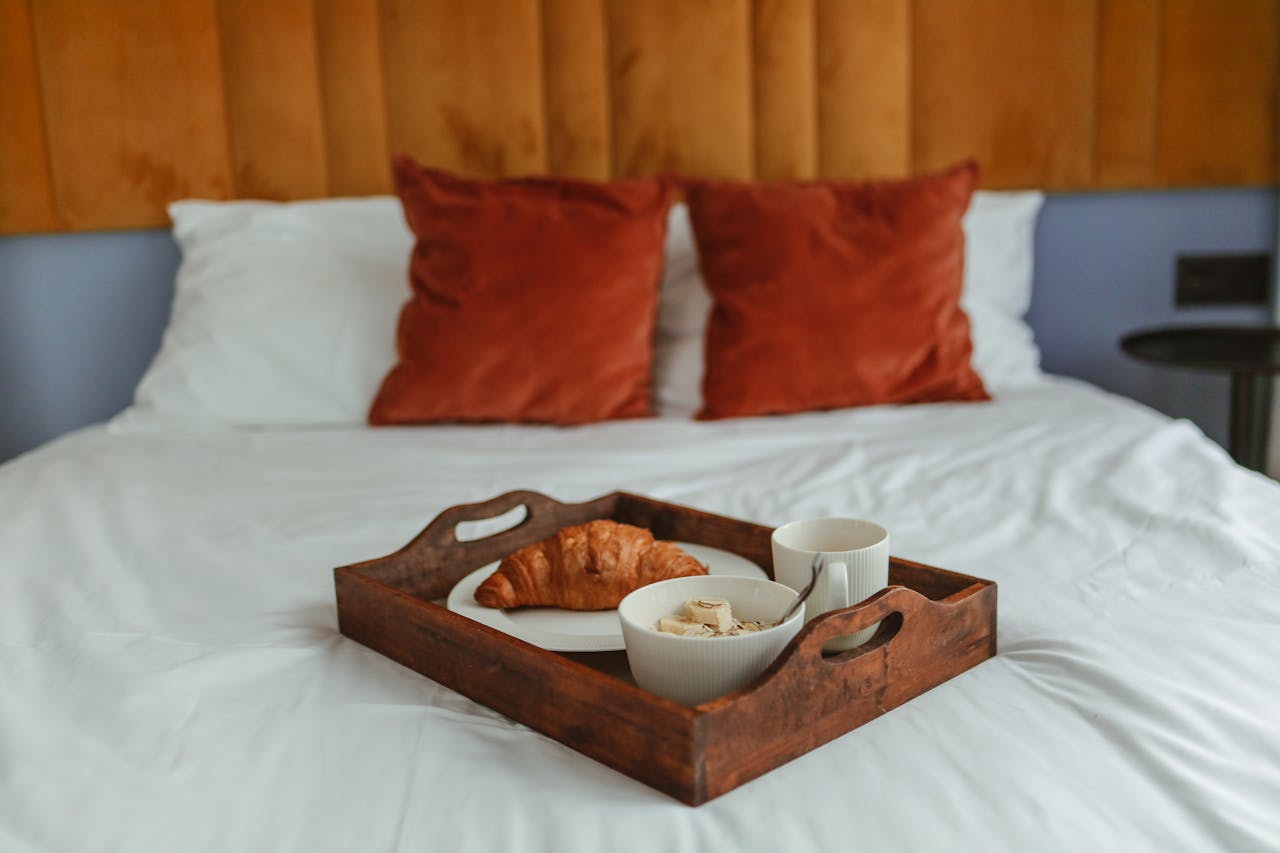 Inviting scene of breakfast in bed featuring a croissant and coffee, creating a warm and relaxing atmosphere.